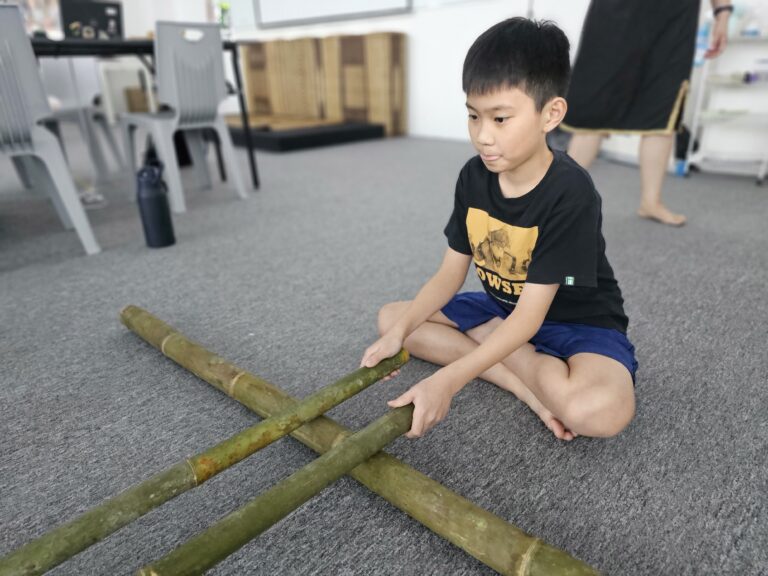 Students practicing teamwork and rhythm in the Bamboo Dance