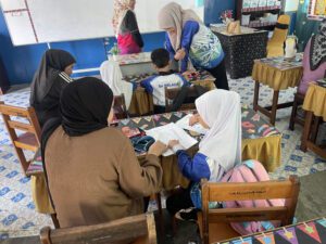 Parent guiding child with Sekolah Enuma digital tool at classroom
